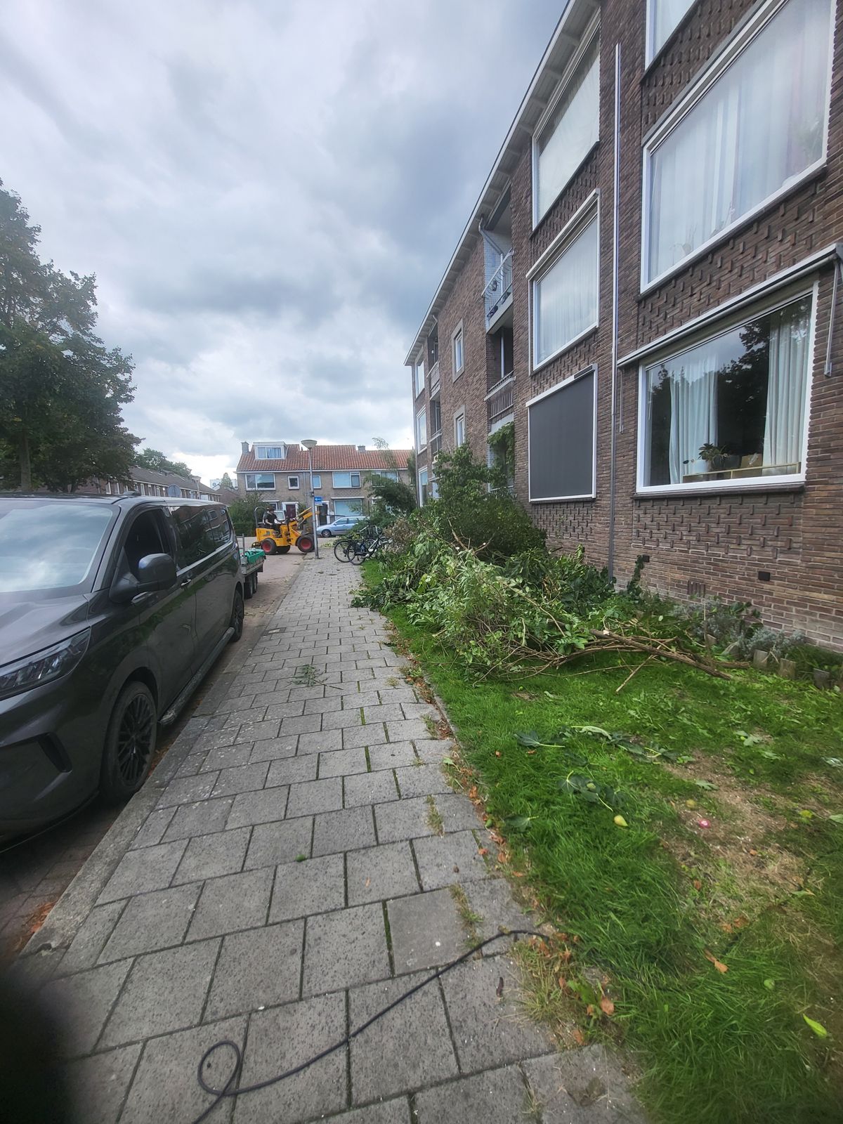 Takken en snoeiafval opruimen bij een flatgebouw