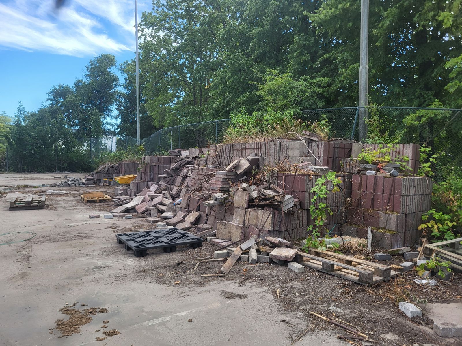 Stapel oude klinkers en pallets op een te ontruimen bedrijfsterrein